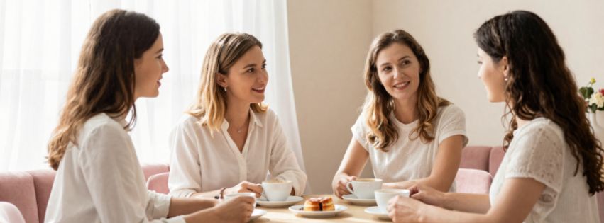 Grupa kobiet wspierających się nawzajem przy kawiarnianym stoliku